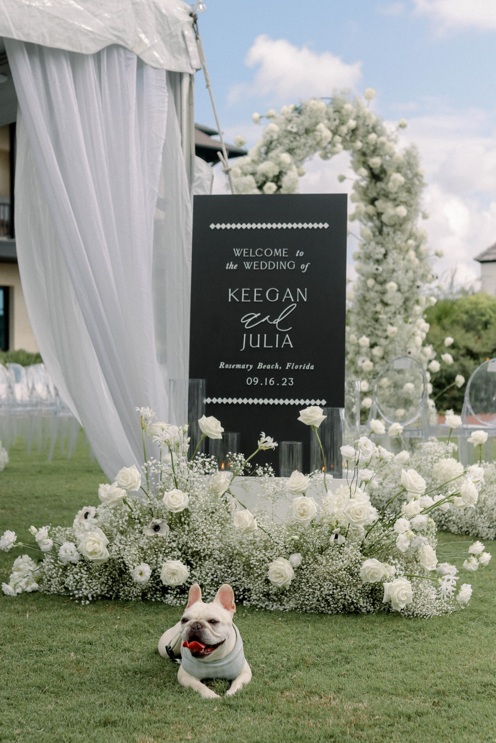 Black wedding welcome sign with white lettering and white florals on the western green at rosemary beach