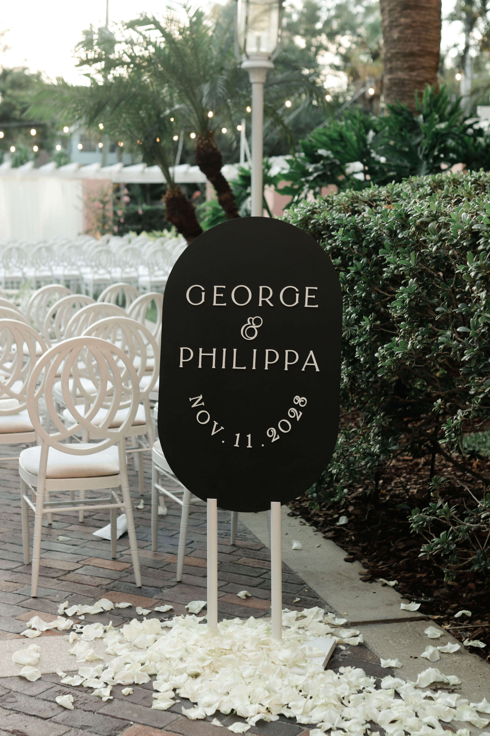 Wedding welcome sign that says "George and Philippa" in a pool of rose petals